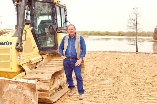 Jimmy King, founder of K.G.W. Corporation, beside a Komatsu dozer