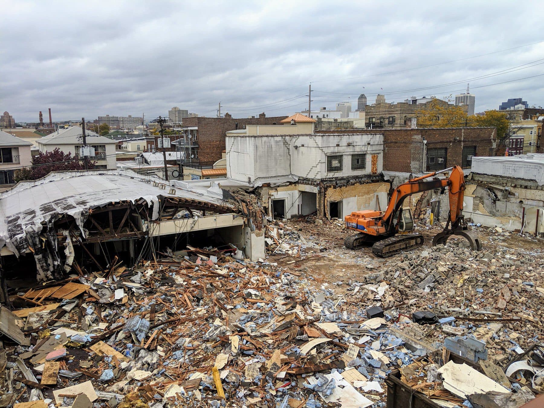 An excavator pulling down a commercial building and sorting the debris for haul-off