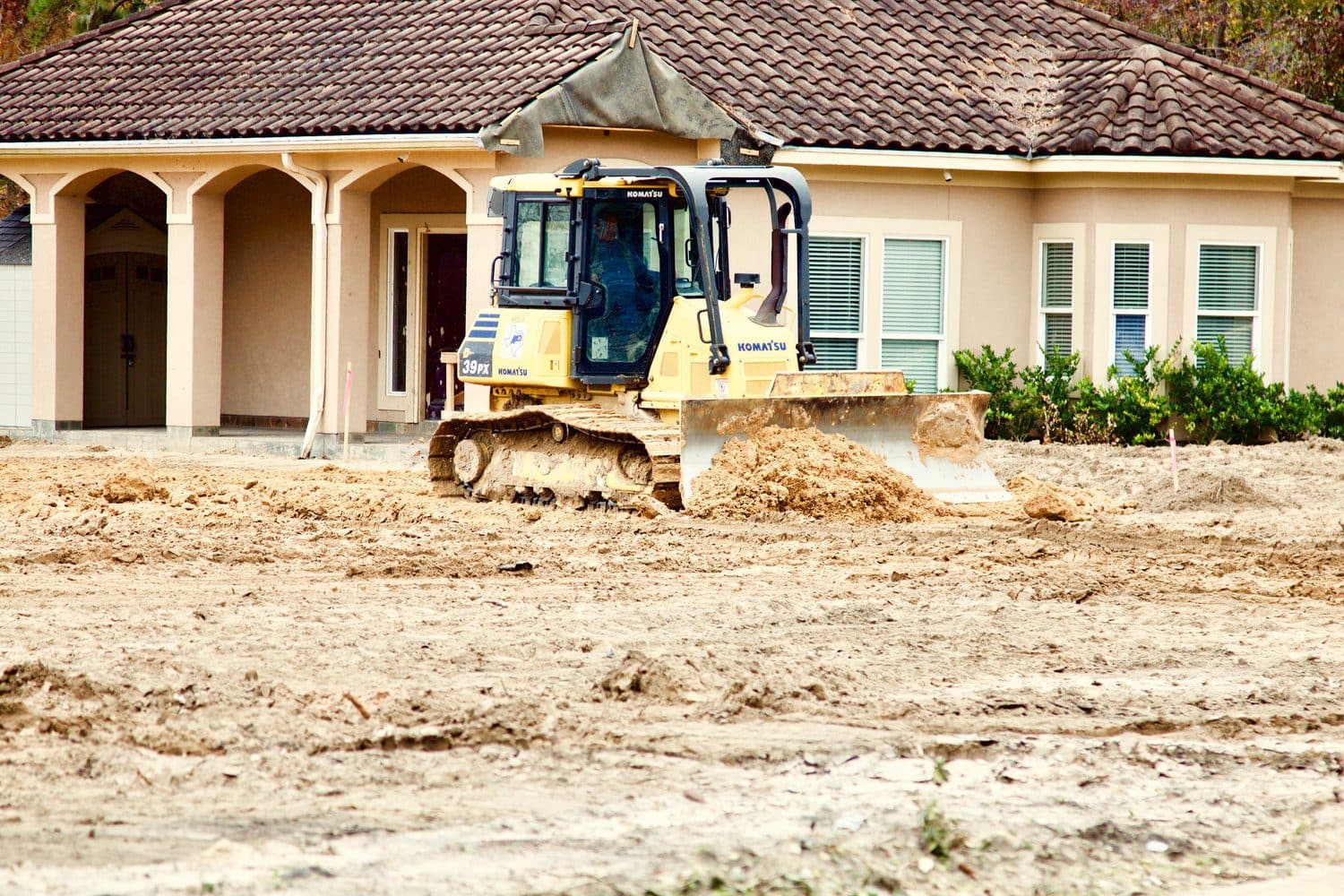 A dozer finishing grade against a newly built Houston-area home
