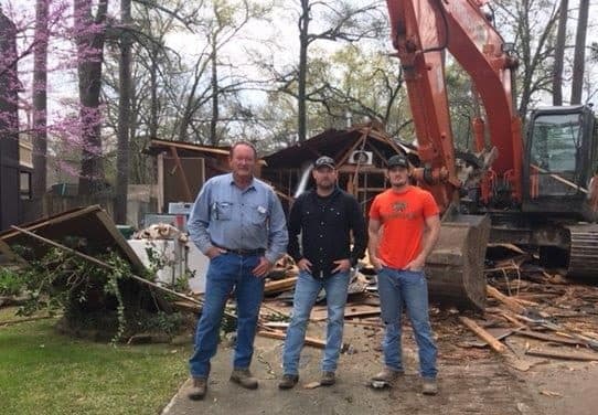 Three generations of the King family standing together in front of a KGW excavator